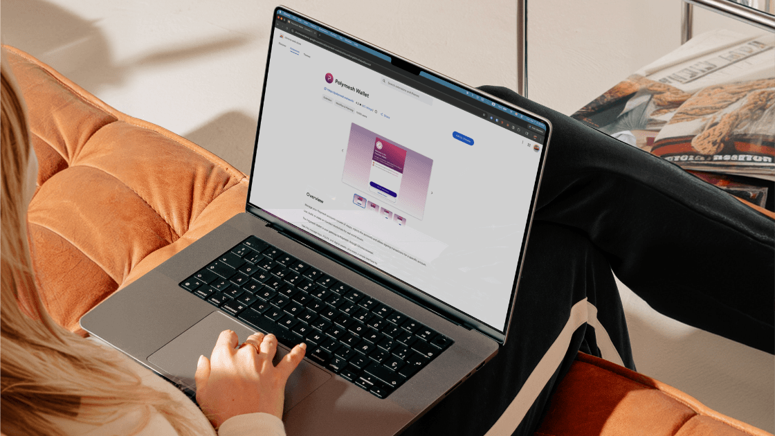 Polymesh Wallet shown on a laptop as someone sits on an orange sofa.